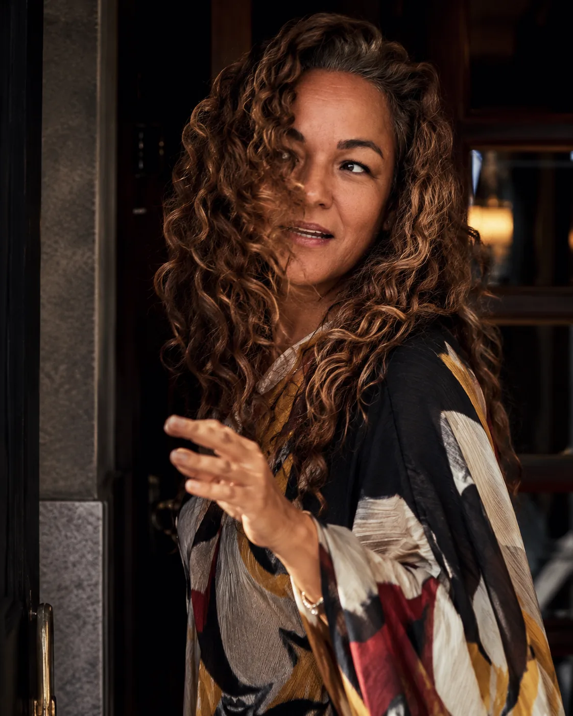 Maria-Inés at a doorway in a printed kimono, looking back over her shoulder