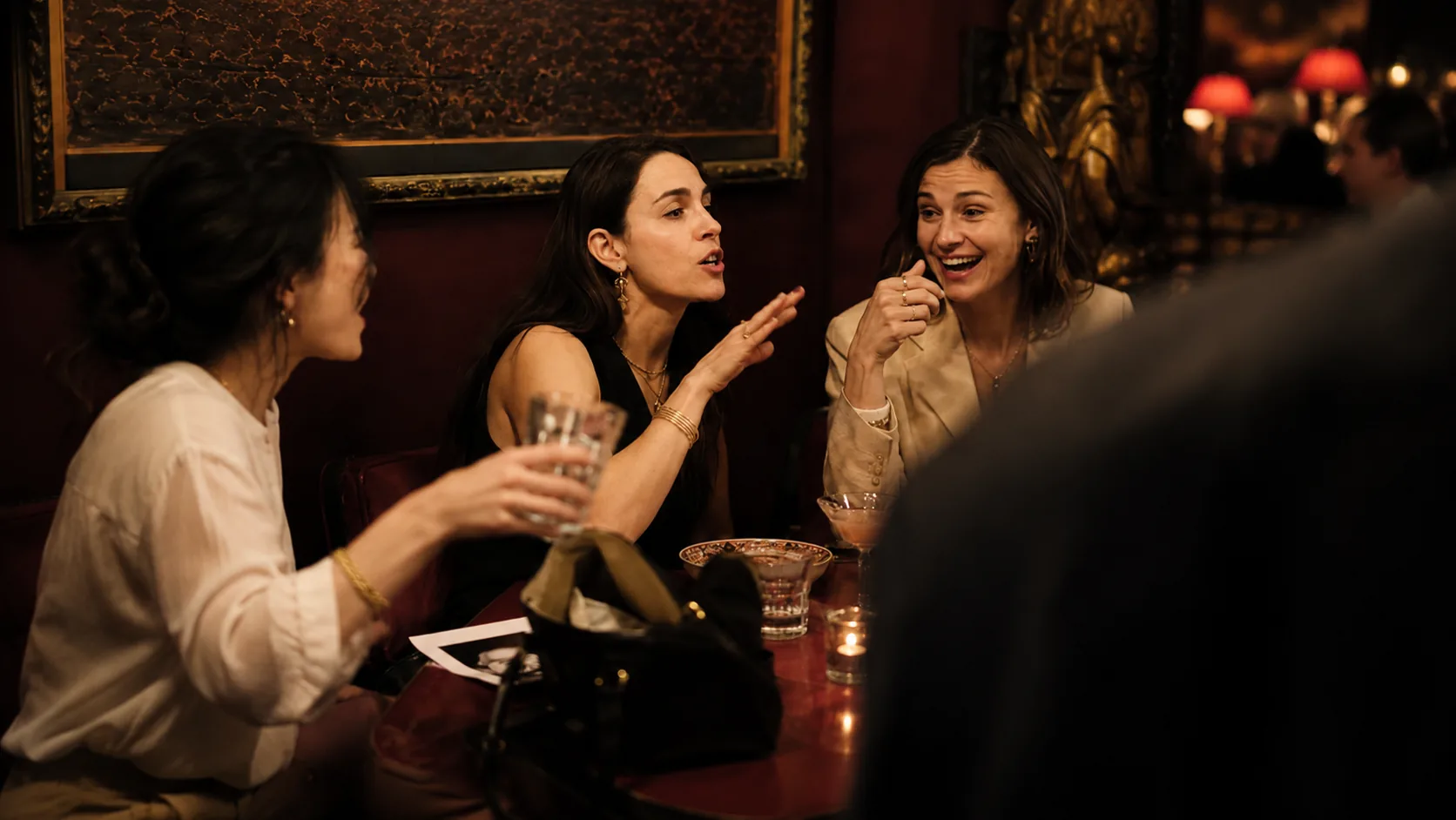 Three women deep in conversation at a restaurant table